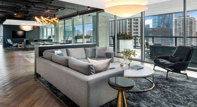 Chic resident lounge with a large gray sofa, stylish decor, and expansive city views at Aston Chicago Apartments