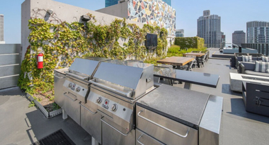 Rooftop patio with modern gas grills, outdoor seating, and panoramic views of the Chicago skyline at Aston Chicago Apartments