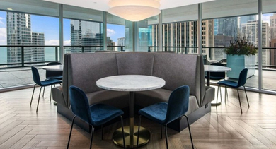 Stylish rooftop lounge with comfortable seating, large windows, and panoramic city views at Aston Chicago Apartments