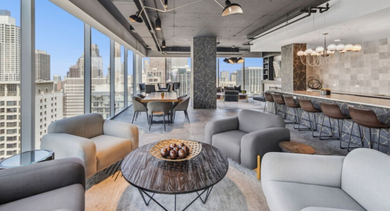 Luxurious sky lounge with plush armchairs, a large coffee table, and a stylish bar area at Aston Chicago Apartments
