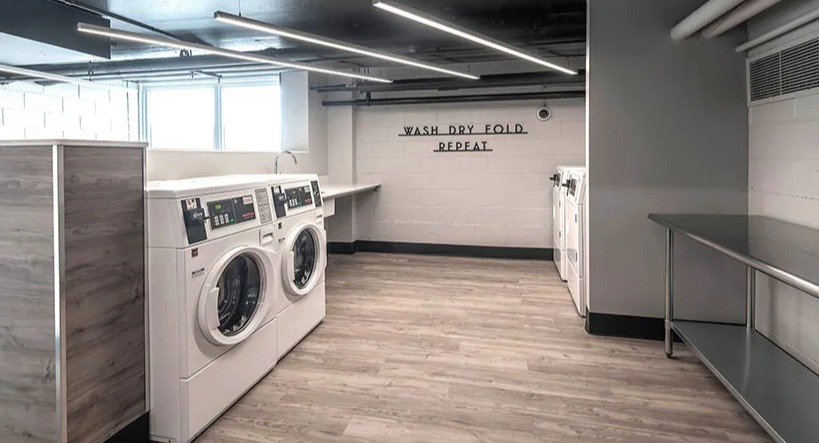 Convenient laundry room with multiple washing machines, folding tables, and bright lighting at Astor House Apartments in Chicago