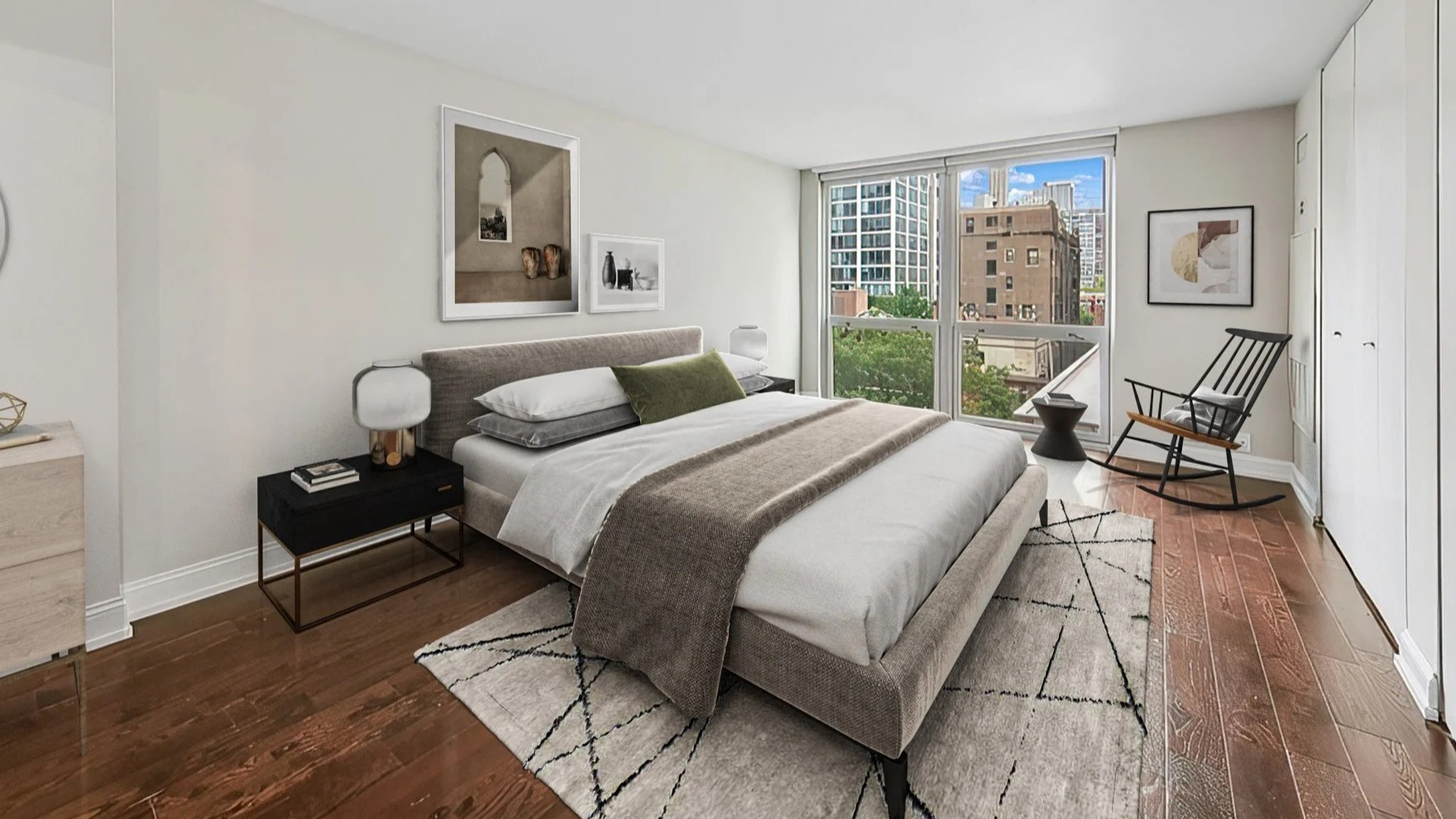 Cozy bedroom with a comfortable bed, minimal decor, and a large window offering city views at Astor House Apartments in Chicago