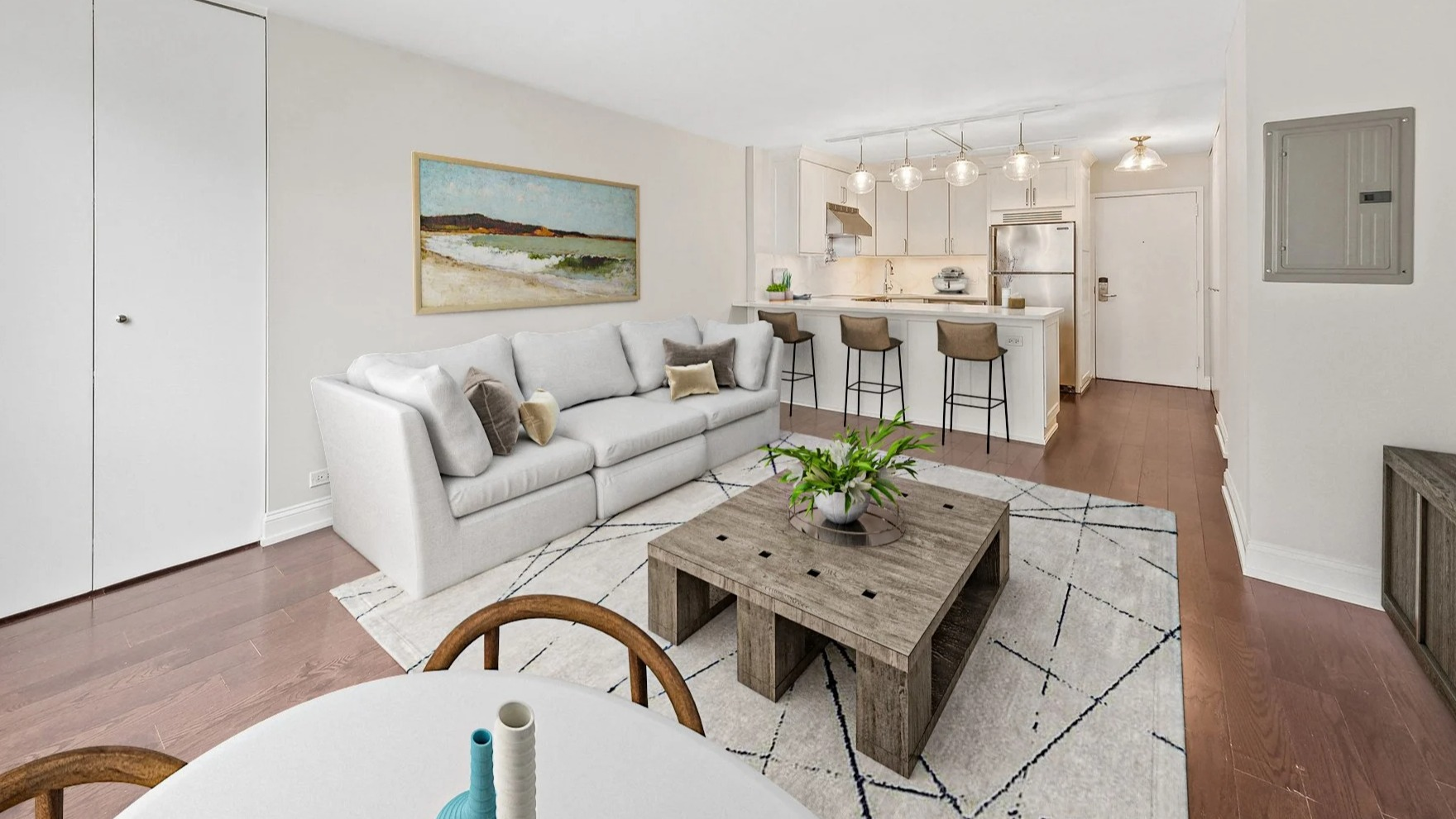 Cozy living room with a white sofa, coffee table, and open-concept kitchen with a breakfast bar at Astor House Apartments in Chicago