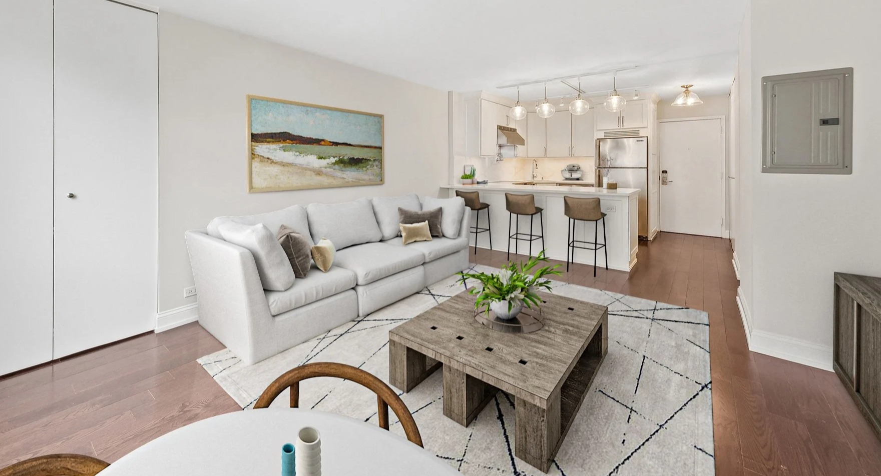 Cozy living room with a white sofa, coffee table, and open-concept kitchen with a breakfast bar at Astor House Apartments in Chicago