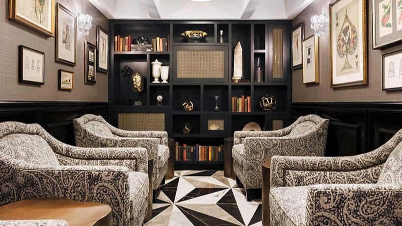 Elegant library lounge with patterned armchairs, dark bookshelves, and unique geometric floor tiles at Astor House Apartments in Chicago