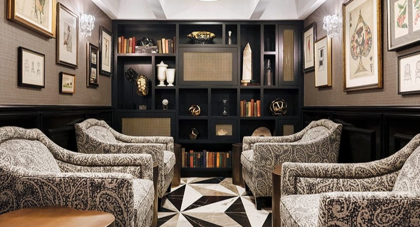 Elegant library lounge with patterned armchairs, dark bookshelves, and unique geometric floor tiles at Astor House Apartments in Chicago