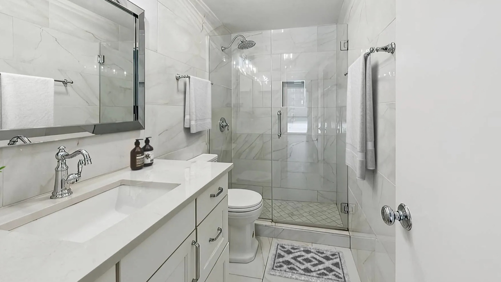 Modern bathroom with a glass-enclosed shower, white vanity, and contemporary fixtures at Astor House Apartments in Chicago