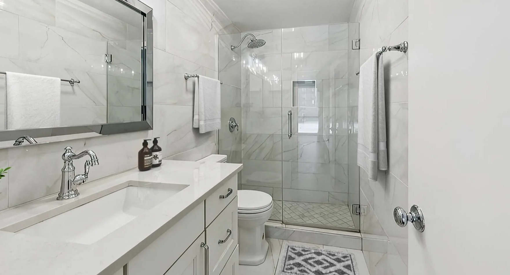 Modern bathroom with a glass-enclosed shower, white vanity, and contemporary fixtures at Astor House Apartments in Chicago