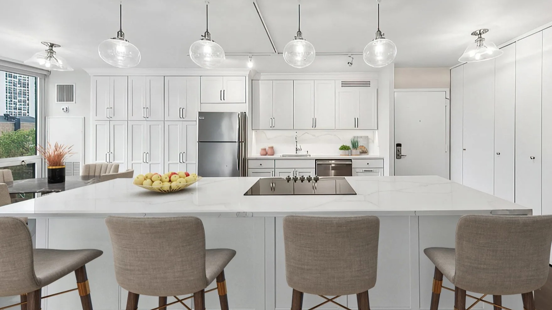 Modern kitchen with white cabinets, large island with bar seating, and stainless steel appliances at Astor House Apartments in Chicago