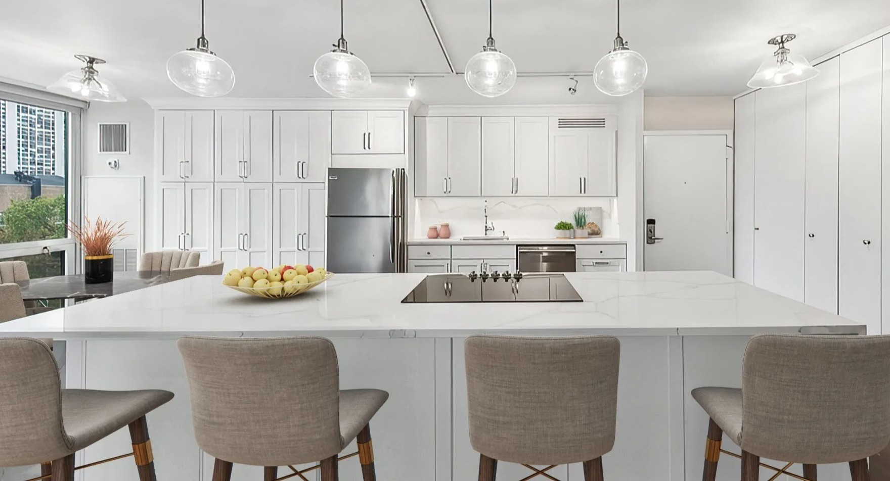 Modern kitchen with white cabinets, large island with bar seating, and stainless steel appliances at Astor House Apartments in Chicago