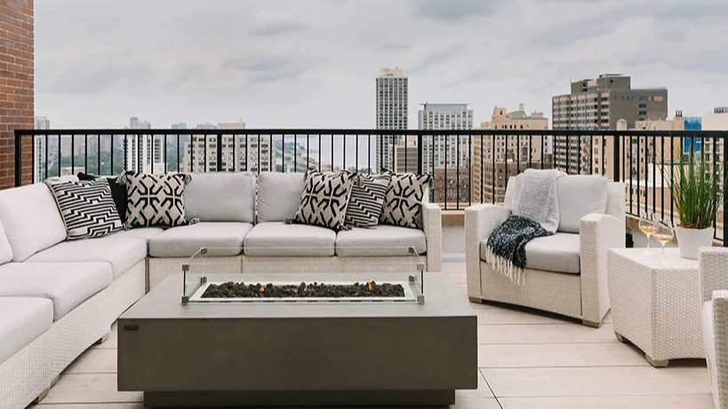 Rooftop lounge area featuring comfortable white seating, a modern fire pit, and expansive city views at Astor House Apartments in Chicago
