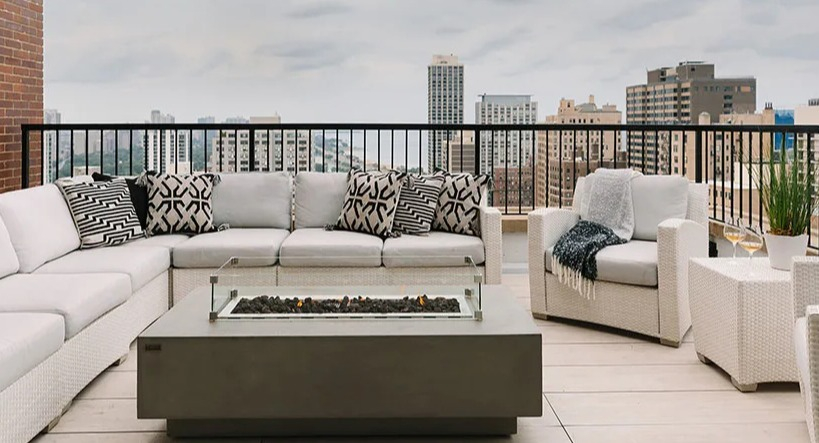 Rooftop lounge area featuring comfortable white seating, a modern fire pit, and expansive city views at Astor House Apartments in Chicago