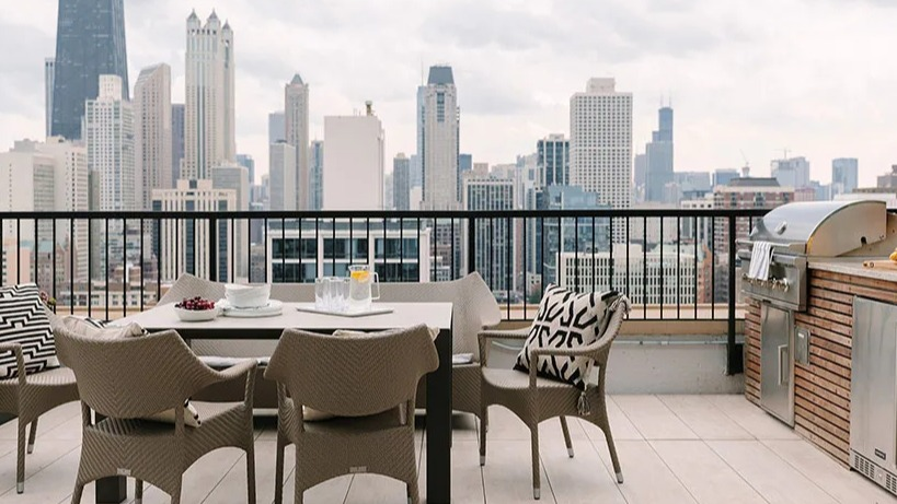 Rooftop patio with outdoor dining, a grill station, and a panoramic Chicago skyline backdrop at Astor House Apartments