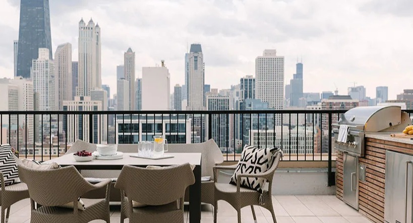 Rooftop patio with outdoor dining, a grill station, and a panoramic Chicago skyline backdrop at Astor House Apartments