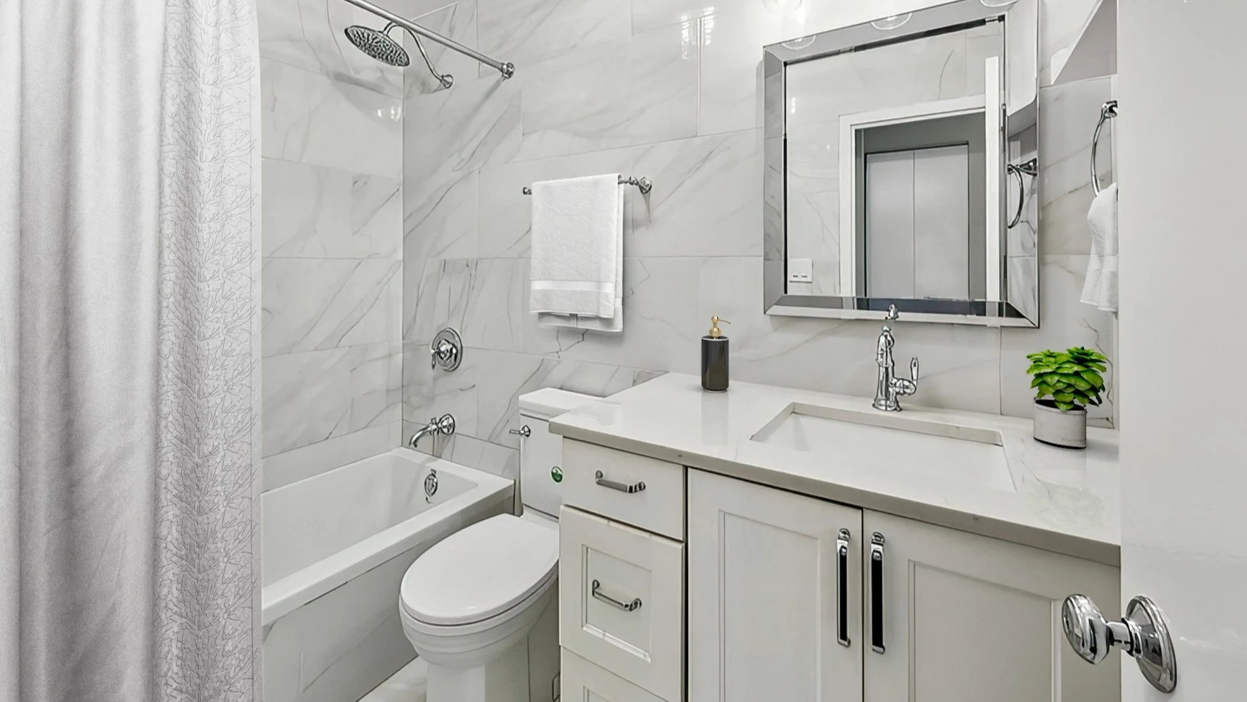 Sleek bathroom with a bathtub, white tiled walls, modern vanity, and reflective mirror at Astor House Apartments in Chicago