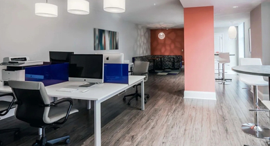 Modern coworking space with individual desks, computers, and a communal high-top table at Astoria Tower Chicago apartments