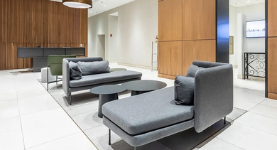 Elegant lobby with contemporary seating, wood paneling, and a clear sign pointing to the mailroom at Astoria Tower Chicago