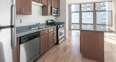 Modern kitchen with wood cabinets, stainless steel appliances, and a granite-topped island at Astoria Tower Chicago apartments
