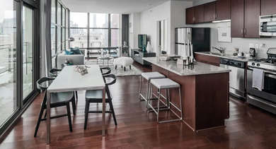 Open-concept living and dining area with a modern kitchen, balcony access, and city views at Astoria Tower Chicago apartments