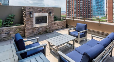Outdoor patio with comfortable seating, an elegant fireplace, and views of surrounding buildings at Astoria Tower Chicago