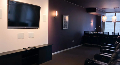 Private movie theater room with comfortable reclining chairs and a large screen for residents at Astoria Tower Chicago apartments