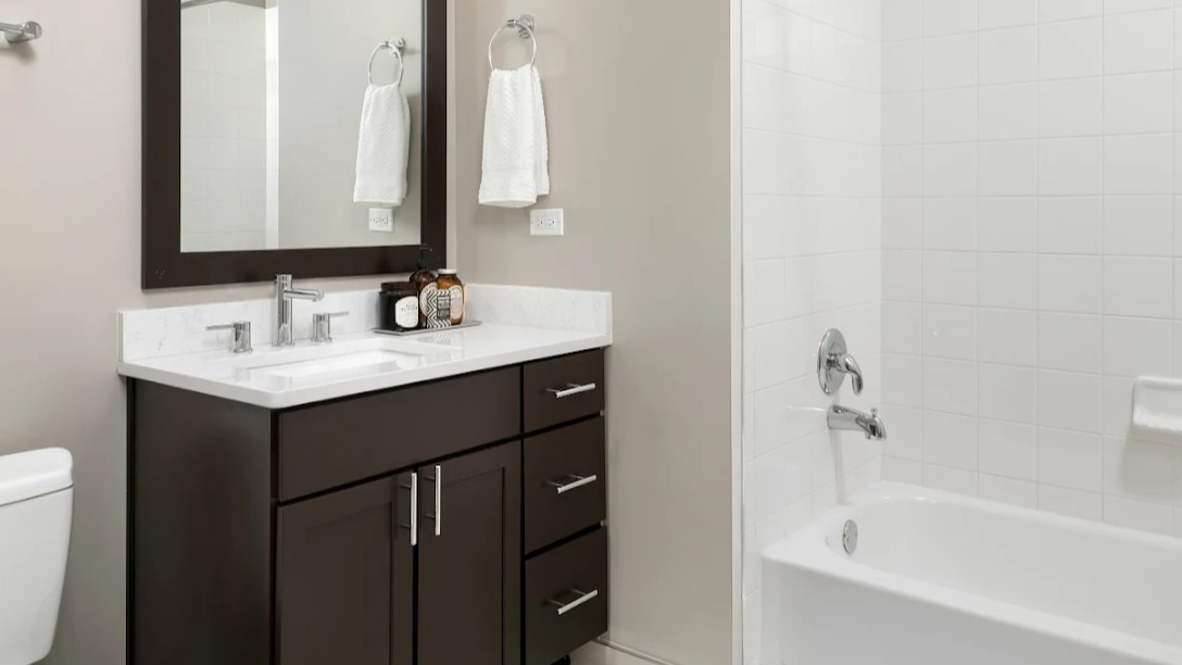 Modern bathroom at Atwater Apartments in Chicago, featuring a sleek vanity, a large mirror, and a combination tub and shower.