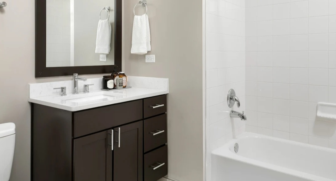 Modern bathroom at Atwater Apartments in Chicago, featuring a sleek vanity, a large mirror, and a combination tub and shower.