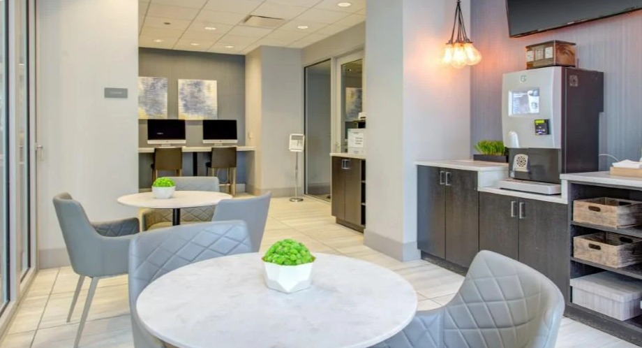 Modern business center and coffee bar area with comfortable seating, computers, and a beverage station at Atwater Apartments in Chicago