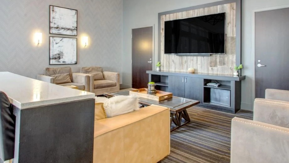 Stylish clubroom at Atwater Apartments in Chicago, featuring comfortable seating, a large TV, and modern geometric lighting fixtures