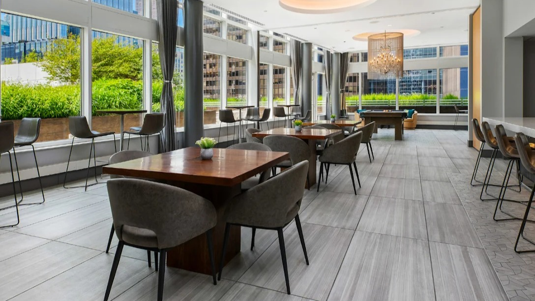 Elegant dining and game area at Atwater Apartments in Chicago, featuring communal tables, a bar, and a view of a pool table