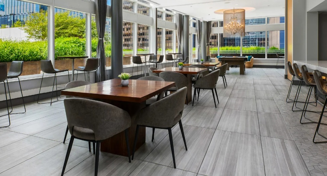 Elegant dining and game area at Atwater Apartments in Chicago, featuring communal tables, a bar, and a view of a pool table