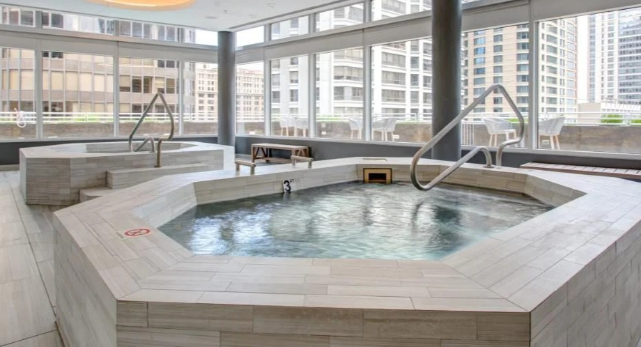Relaxing indoor area featuring two large hot tubs with city views, perfect for unwinding at Atwater Apartments in Chicago