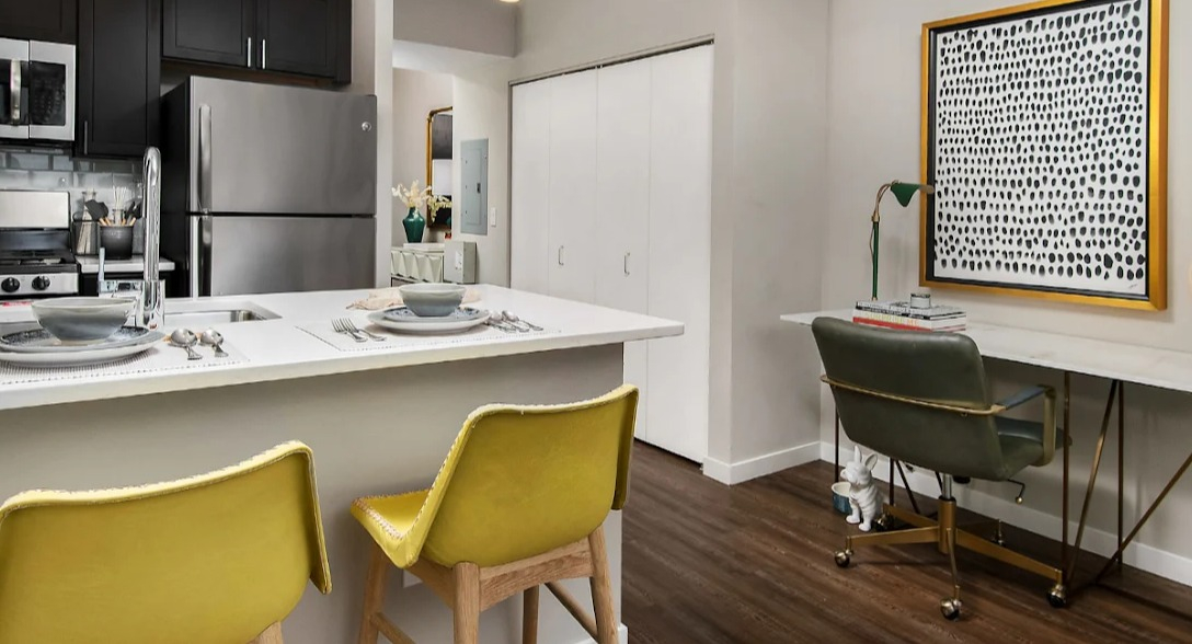 Contemporary kitchen at Atwater Apartments in Chicago, featuring stainless steel appliances, a large island with seating, and an integrated desk area