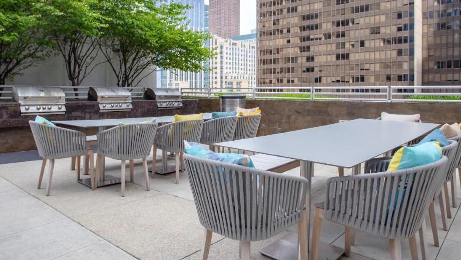 Expansive outdoor patio with multiple grilling stations, spacious dining tables, and lush greenery at Atwater Apartments in Chicago