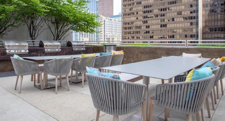 Expansive outdoor patio with multiple grilling stations, spacious dining tables, and lush greenery at Atwater Apartments in Chicago