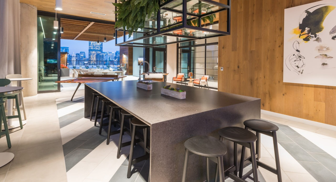 A modern co-working space featuring a large kitchen island, stylish bar stools, and warm lighting