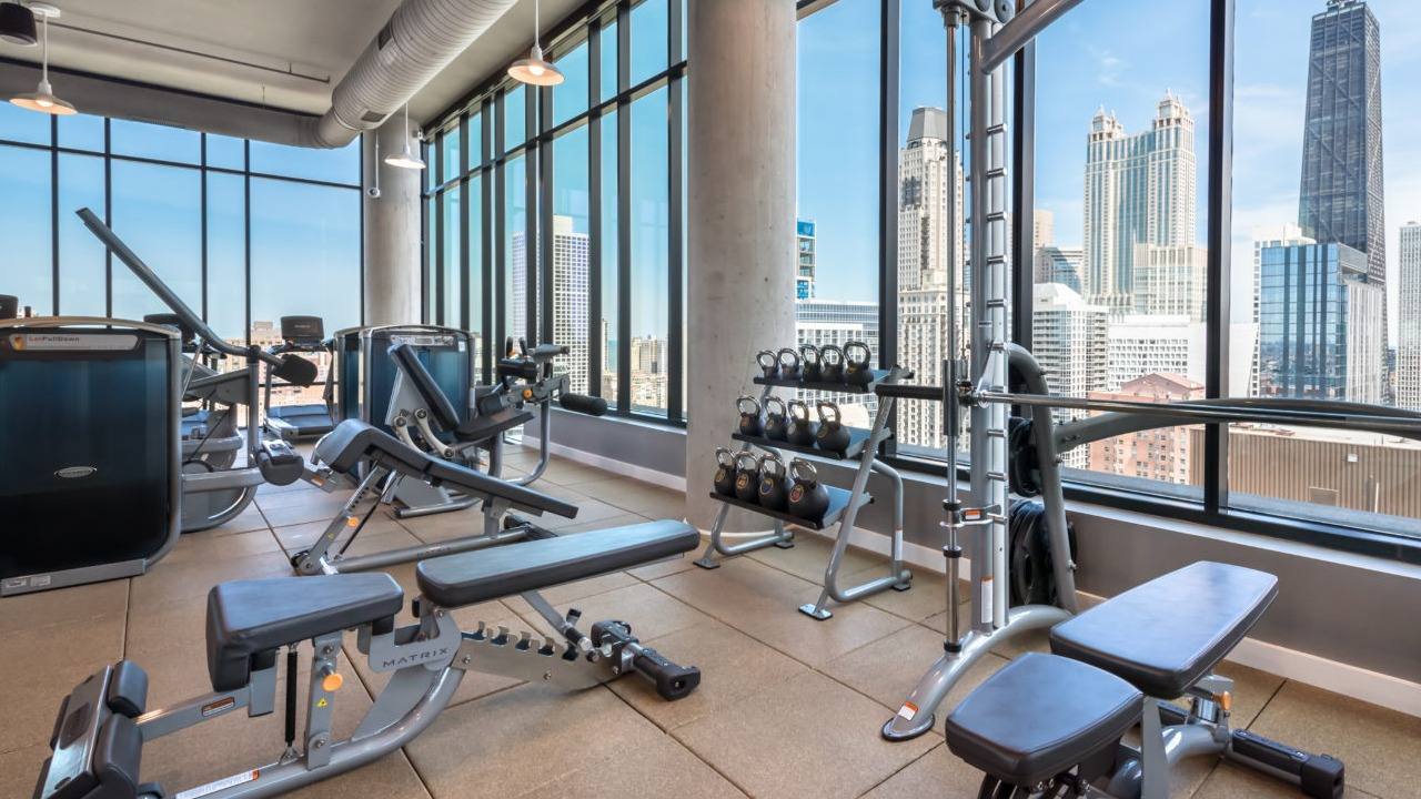 A modern fitness center with various exercise equipment and expansive views of the Chicago skyline