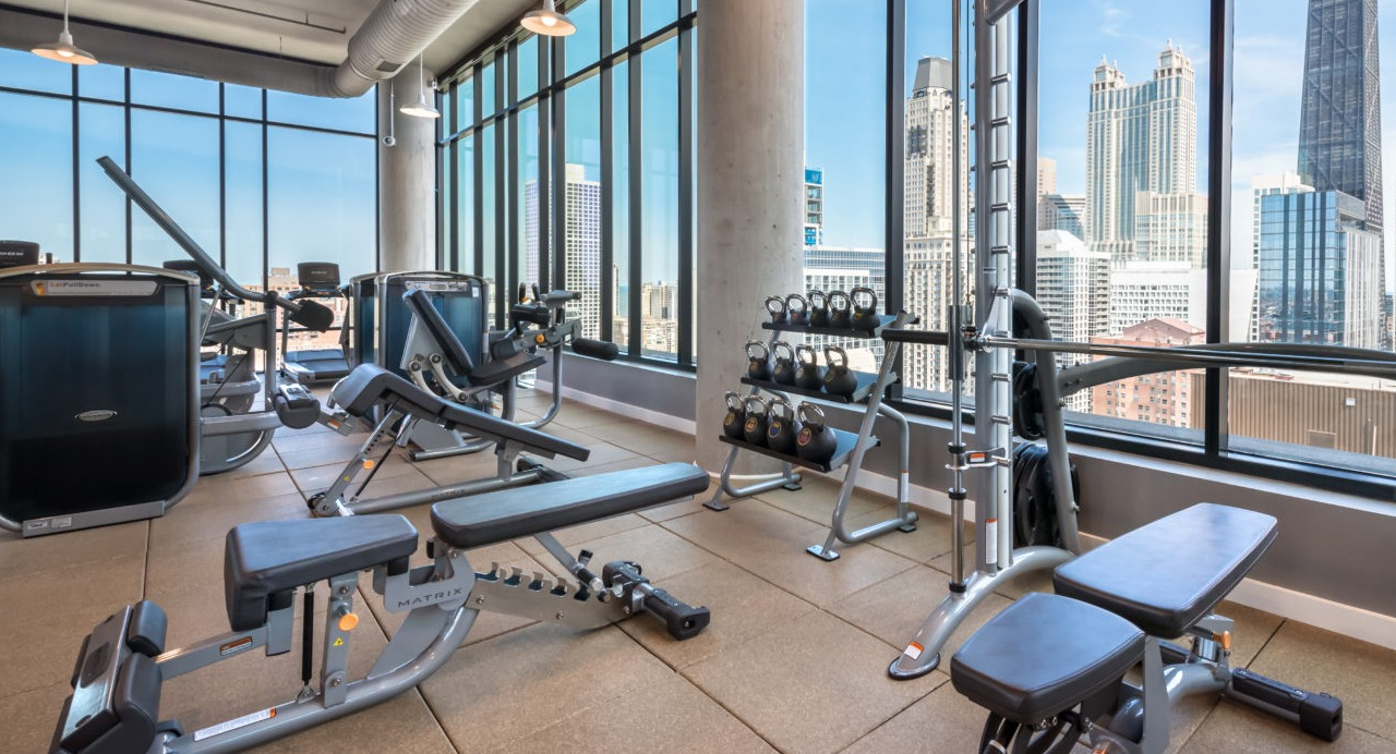 A modern fitness center with various exercise equipment and expansive views of the Chicago skyline