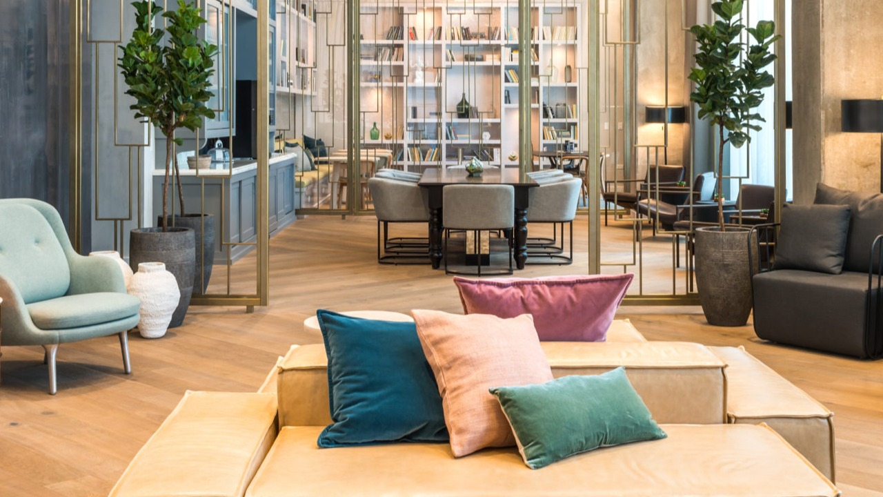 A chic apartment lounge area featuring plush seating, a dazzling chandelier, and sophisticated decor