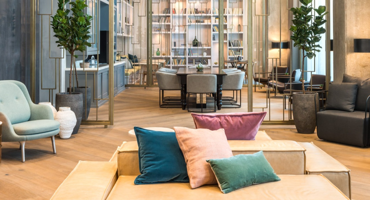 A chic apartment lounge area featuring plush seating, a dazzling chandelier, and sophisticated decor