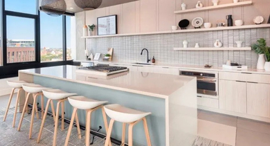 Modern apartment kitchen featuring a large island with bar seating and sleek appliances at Avenir apartments in Chicago