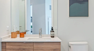 Modern bathroom featuring a floating wood vanity, large mirror, and clean white toilet at Avenir apartments in Chicago