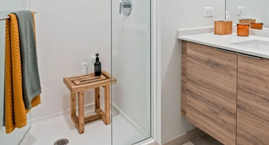 Bright, modern bathroom with a walk-in glass shower, wood vanity, and clean design at Avenir apartments in Chicago