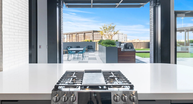 A modern apartment kitchen with a white island and stove, opening to an outdoor amenity space at Avenir apartments in Chicago