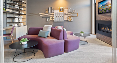 Stylish lounge area with a unique purple sectional sofa, fireplace, and artistic wall decor at Avenir apartments in Chicago