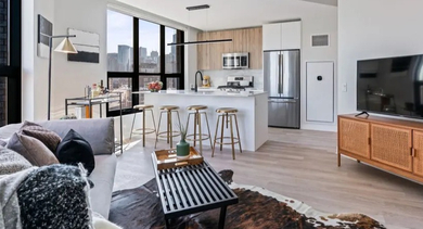 Open-concept living room and kitchen area with modern decor, stainless steel appliances, and city views at Avenir apartments in Chicago