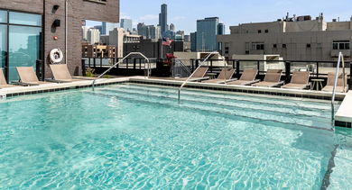 Stunning rooftop swimming pool with lounge chairs and panoramic Chicago skyline views at Avenir apartments