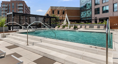 A chic poolside sun deck with comfortable lounge chairs and a view of the adjacent building at Avenir apartments in Chicago
