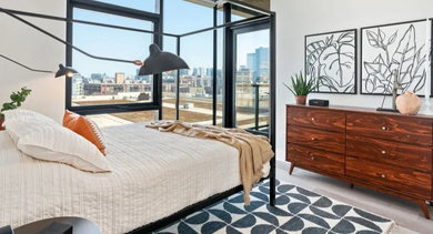 A modern bedroom featuring a black canopy bed and city views at Avra West Loop apartments in Chicago