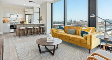 Spacious living room with a vibrant yellow sofa and city views at Avra West Loop apartments in Chicago